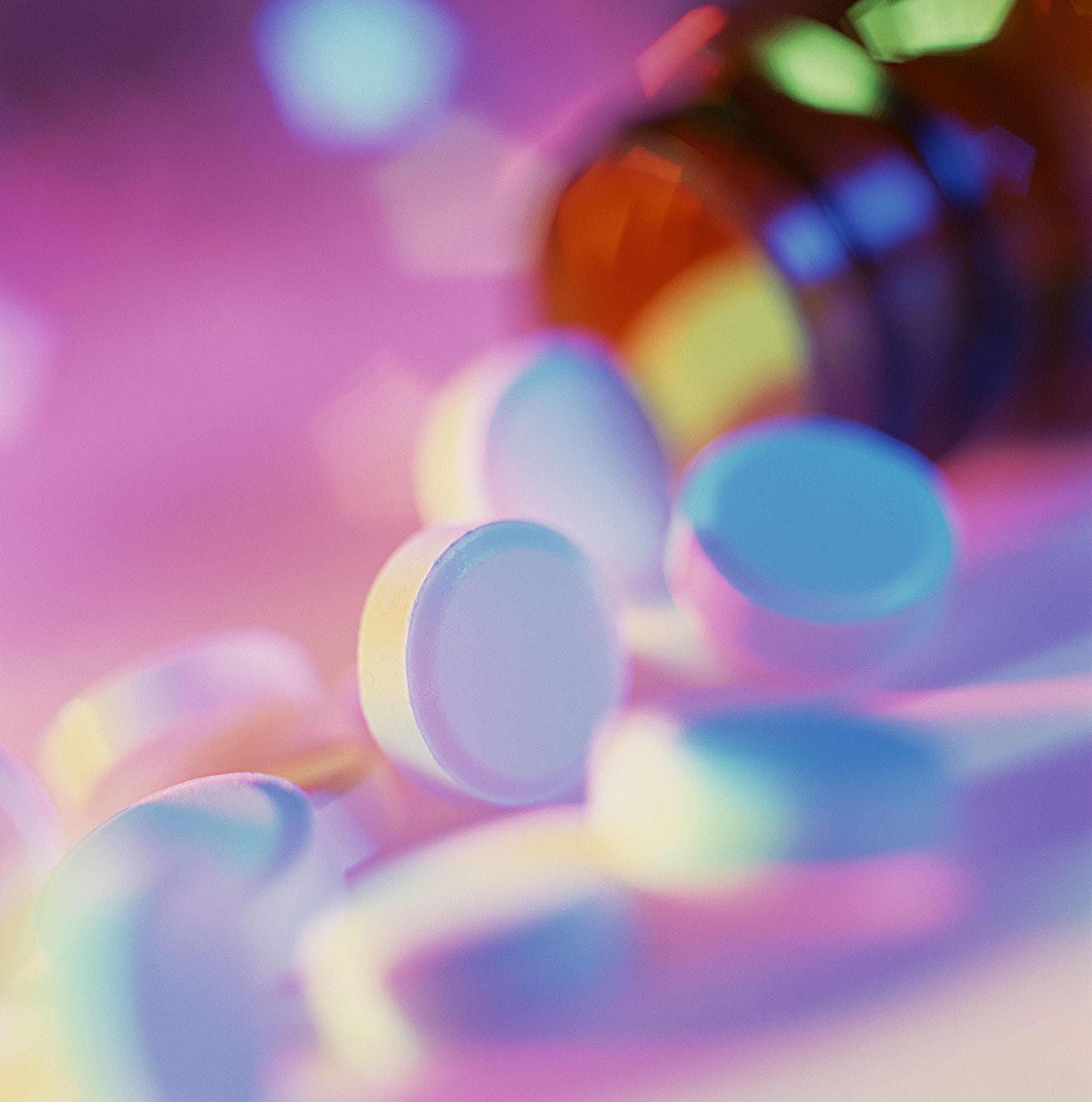 Tablets and a medicine bottle in soft pink and blue light