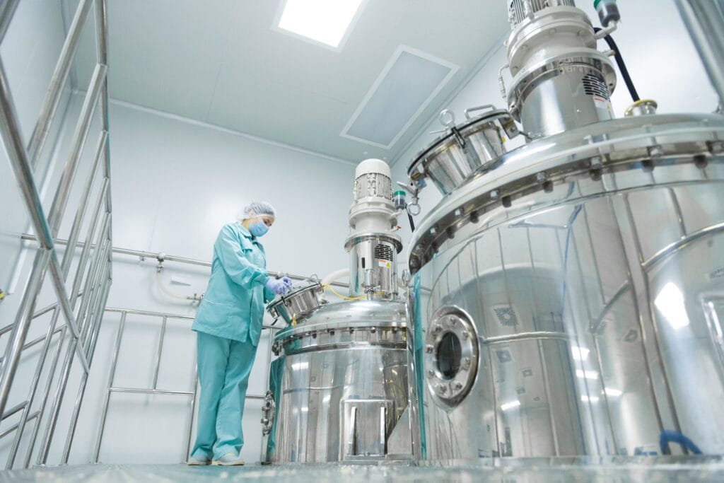 Worker in a cleanroom with large stainless-steel process vessels